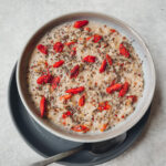 Grey bowl filled with quinoa, bulgur and oatmeal porridge with goji berries and chia seeds